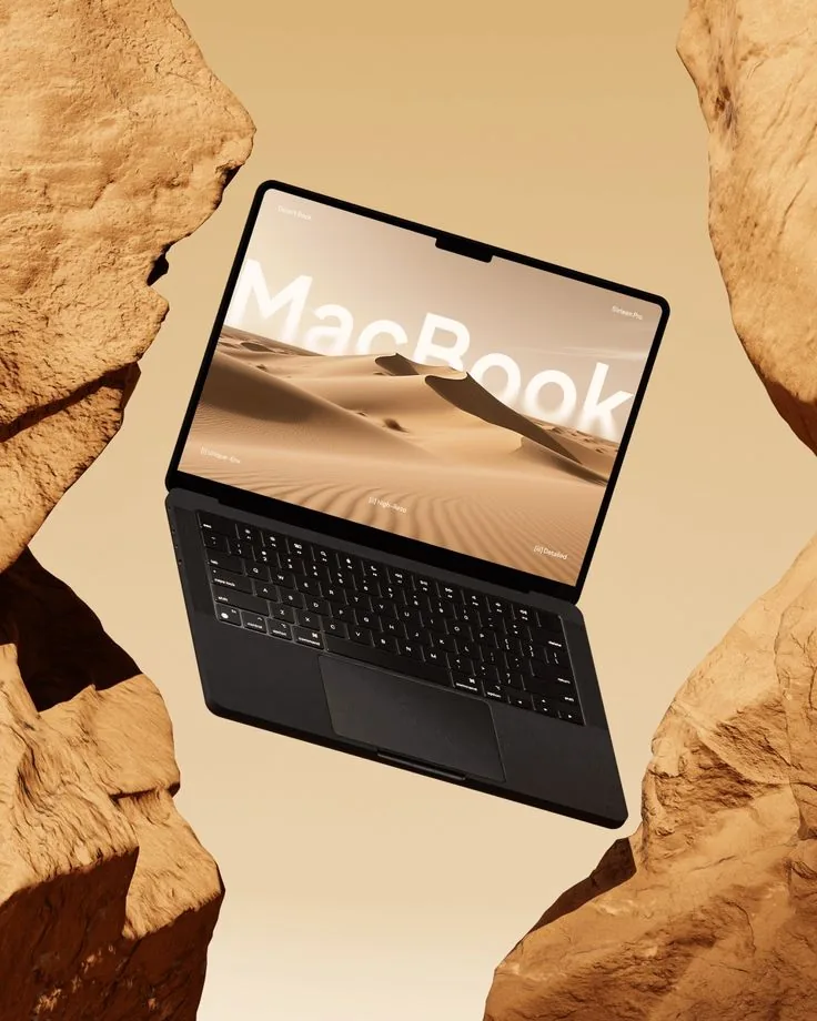 A dark MacBook floating between sandstone rocks